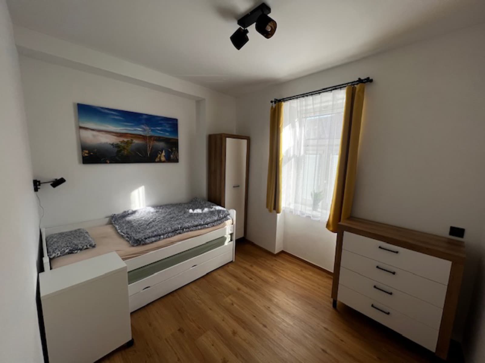 ložnice se skříní a komodou